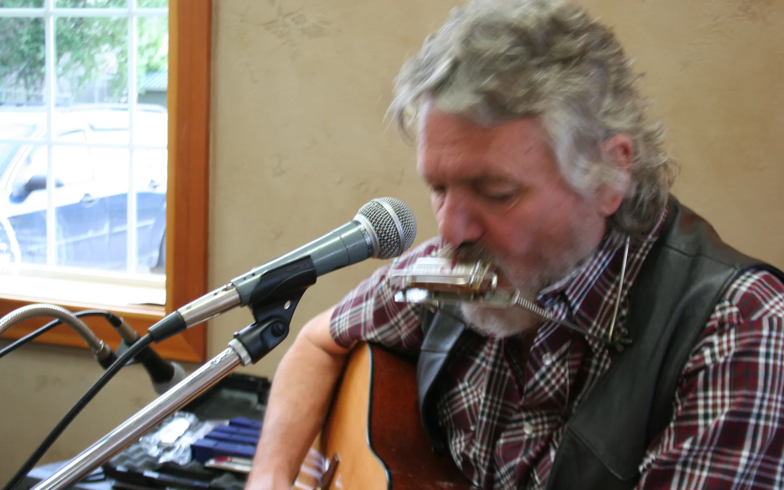 Michael Seward performing with acoustic guitar and harmonica