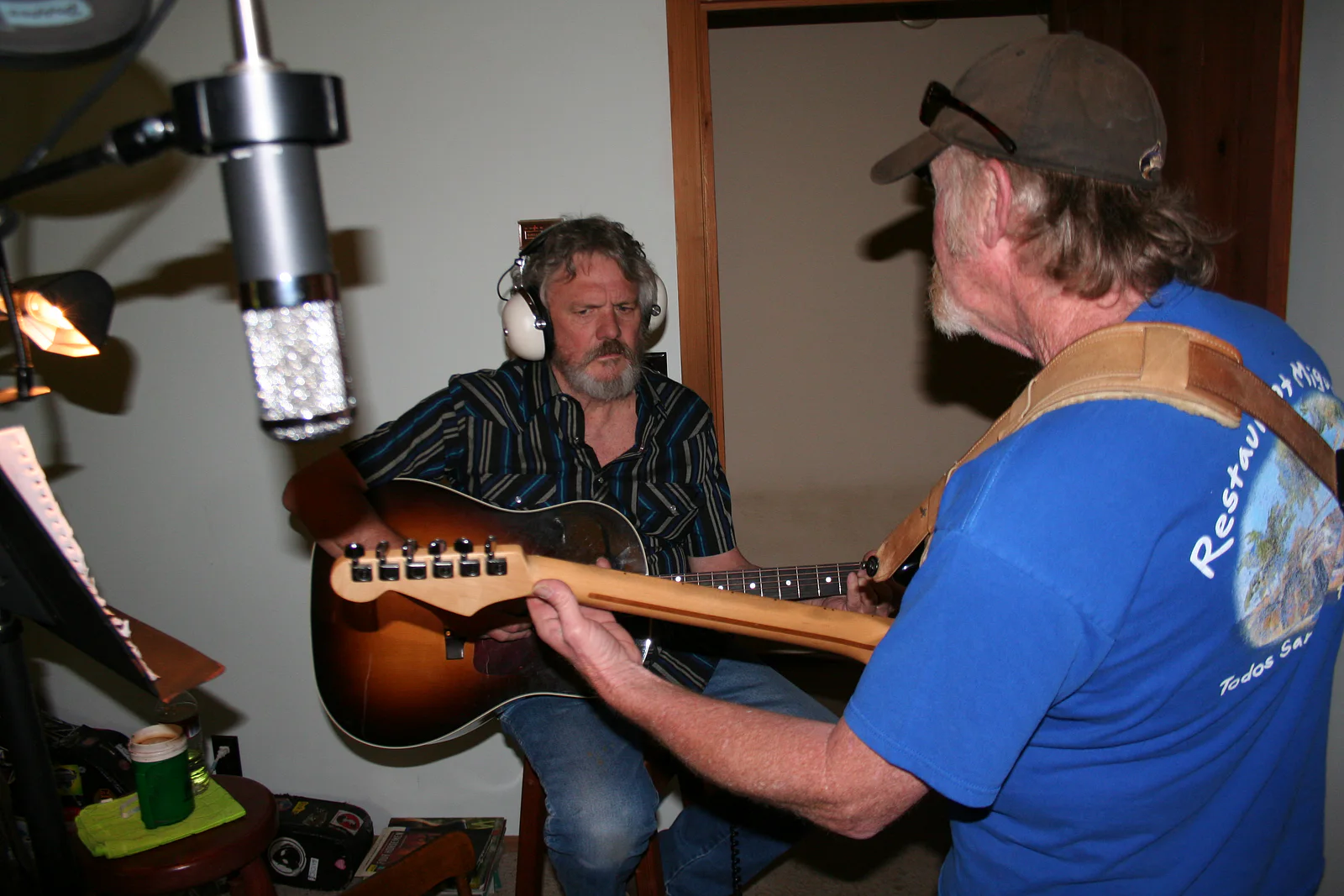 Michael Seward and Johnny Napp concentrating on their guitar parts beneath a studio microphone